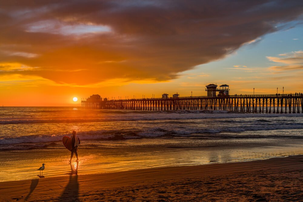A dramatic sunset at Oceanside pier in north San Diego and a surfer calling it a day