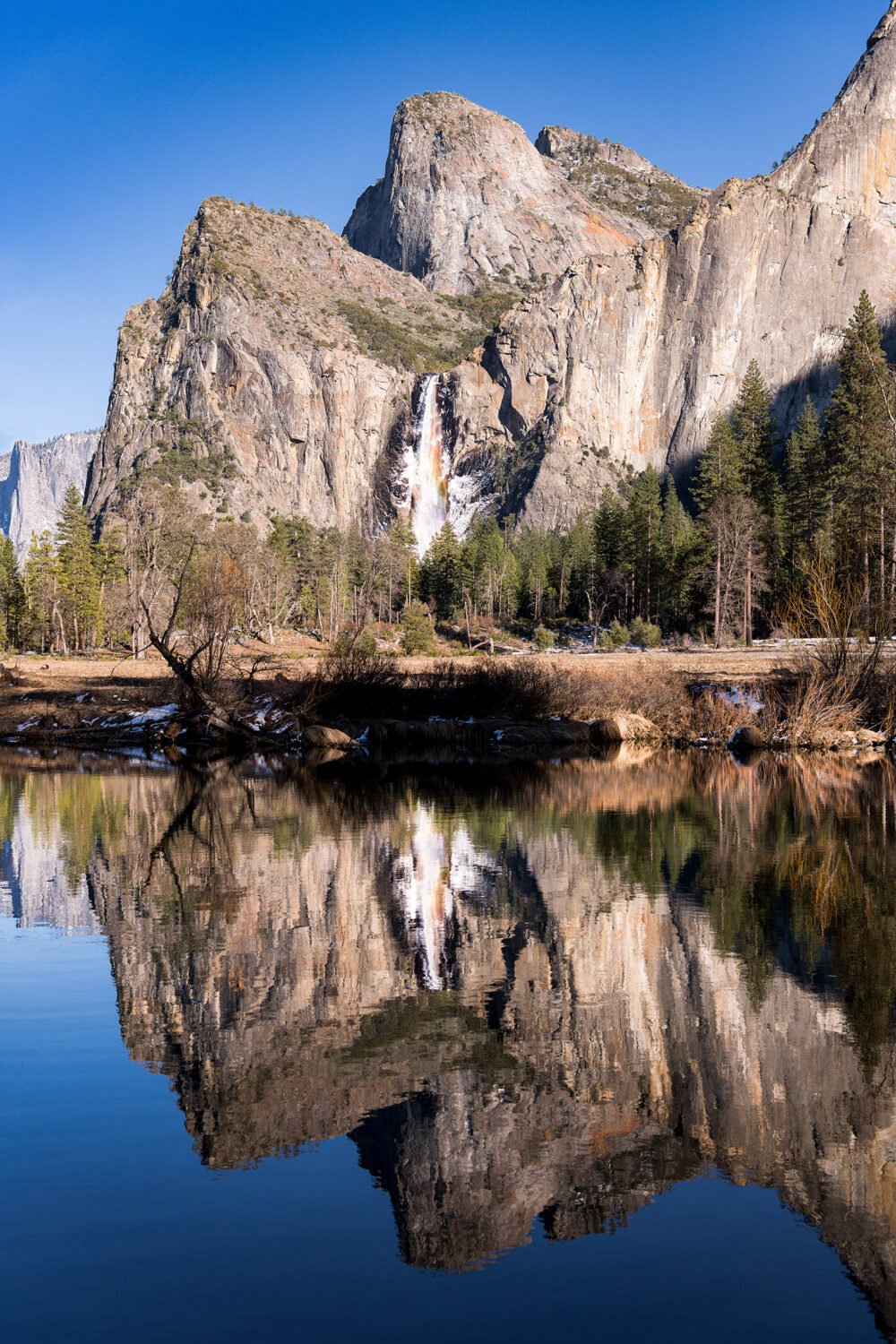 Nearly frozen Bridalveil Fall reflecting in the Merced River in winter. Bridalveil Fall is one of Yosemite's most popular waterfalls.