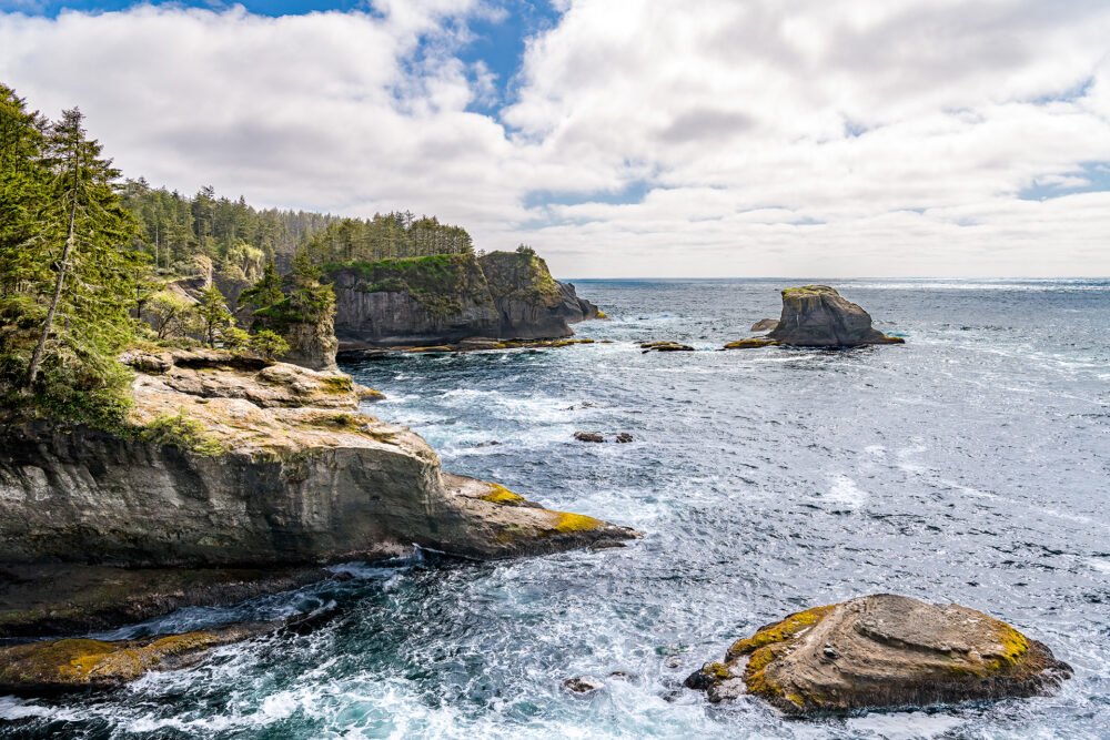 At Cape Flattery in the state of Washington, forest covered bluffs, cliffs and sea stacks meet the Pacific Coast.