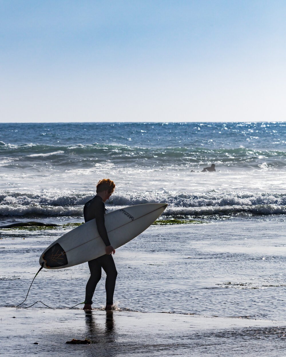 A lone surfer heads into the waves at Swami's Beach on the California Coast