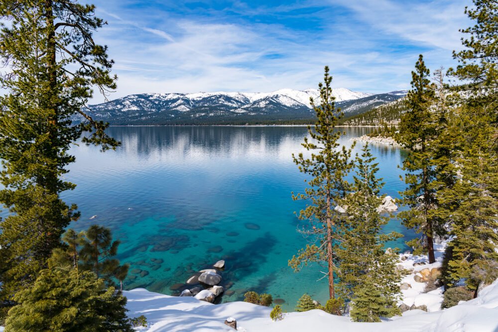 A pristine cove at Lake Tahoe with incredibly clear water and snowcapped mountains