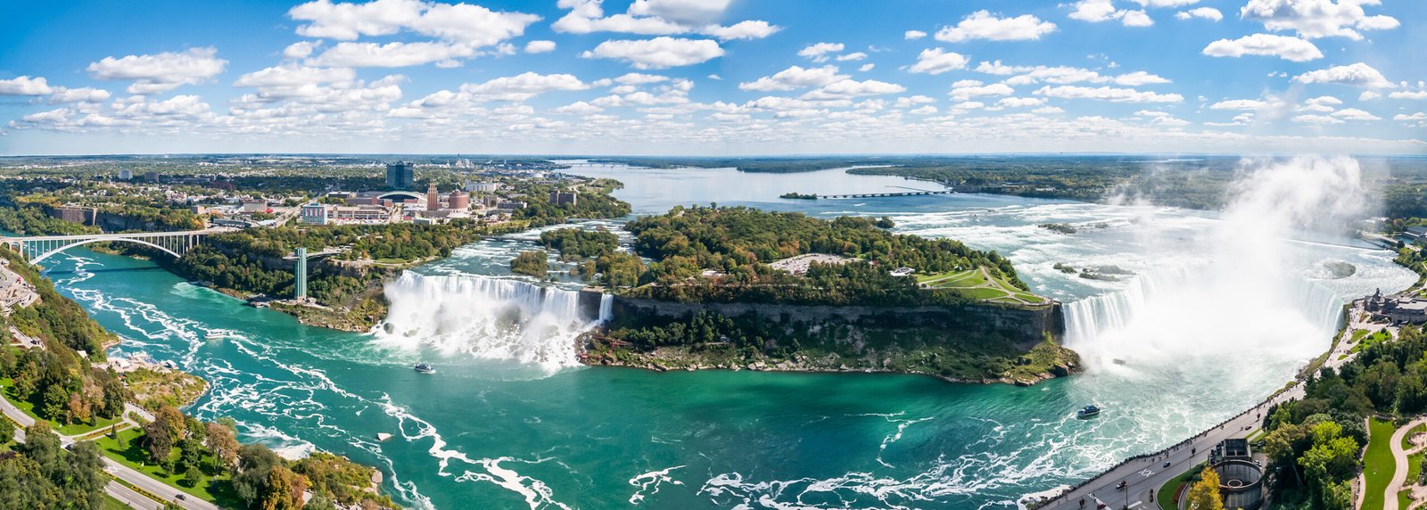 The three magnificent waterfalls and the Niagara River that comprise the famous Niagara Falls are captured in the aerial panorama
